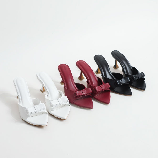 Set of four high-heeled shoes in white, maroon and black on a light gray background
