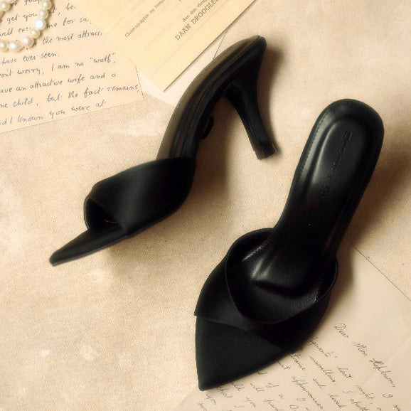 Black high-heeled shoes on a textured surface with handwritten text
