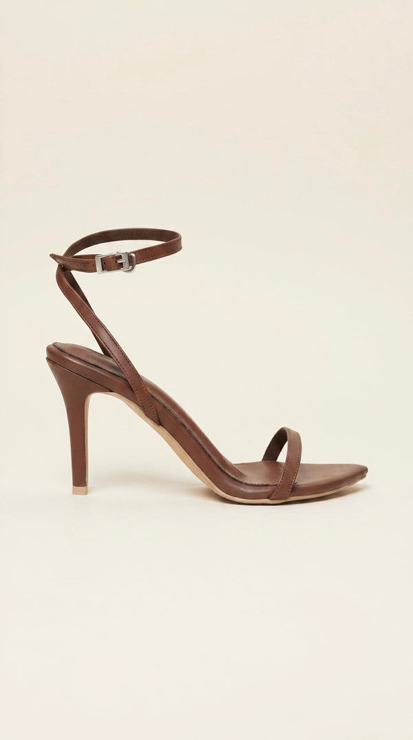 dark Brown high-heeled sandal with thin straps on a beige background