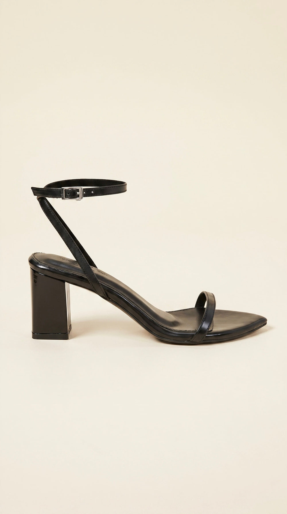 Black sandal with a block heel on a beige background