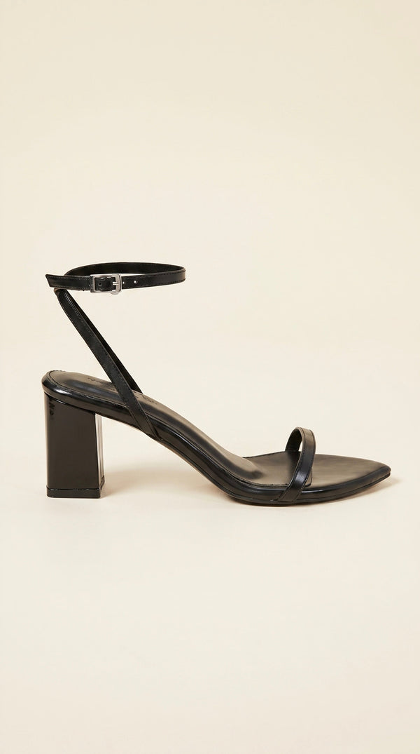 Black sandal with a block heel on a beige background