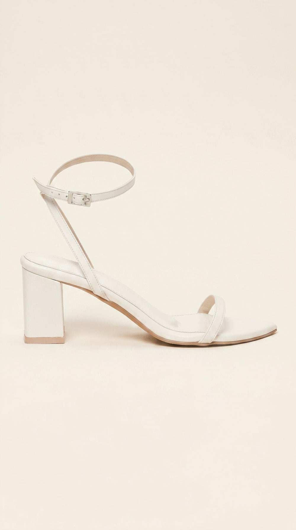 White sandal with block heel on a beige background
