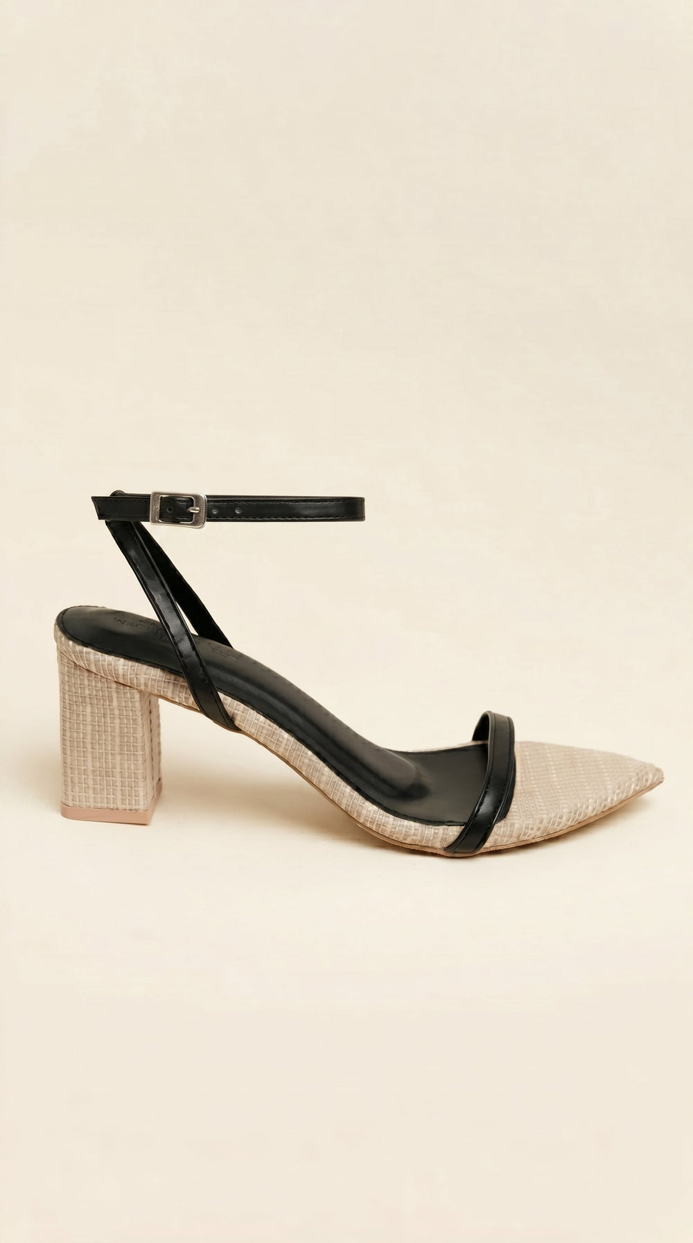 Beige sandal with black ankle strap on a beige background