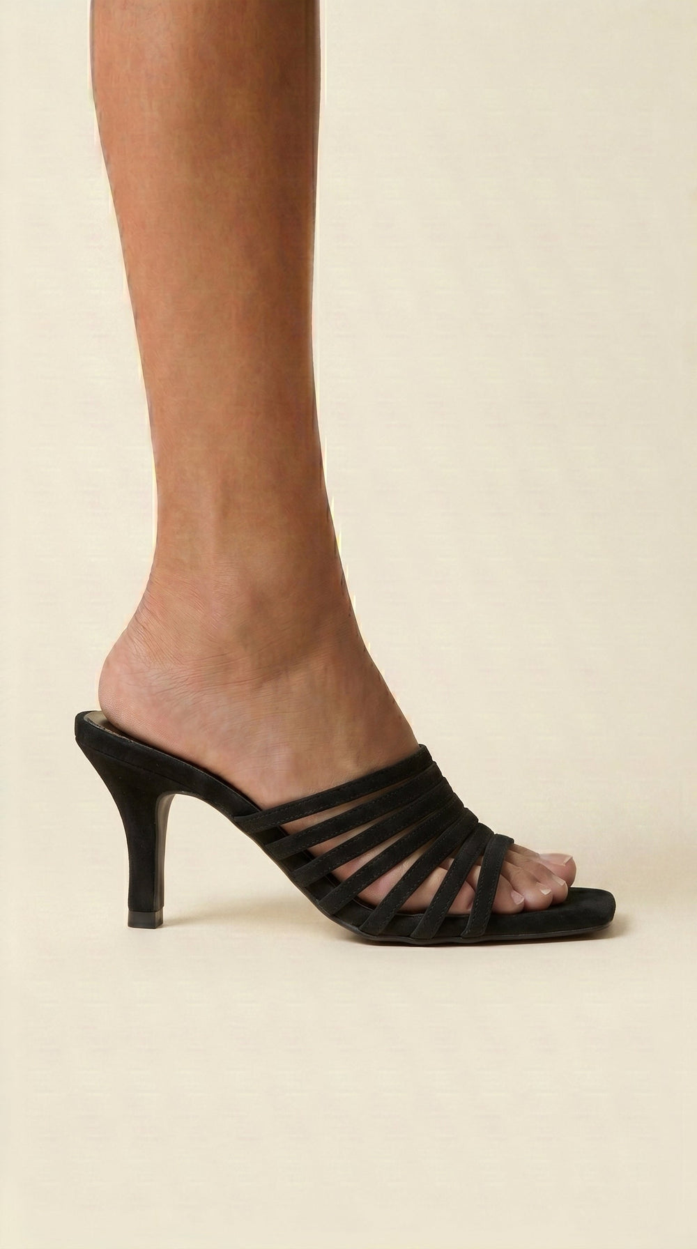 Black suede sandal on a beige background