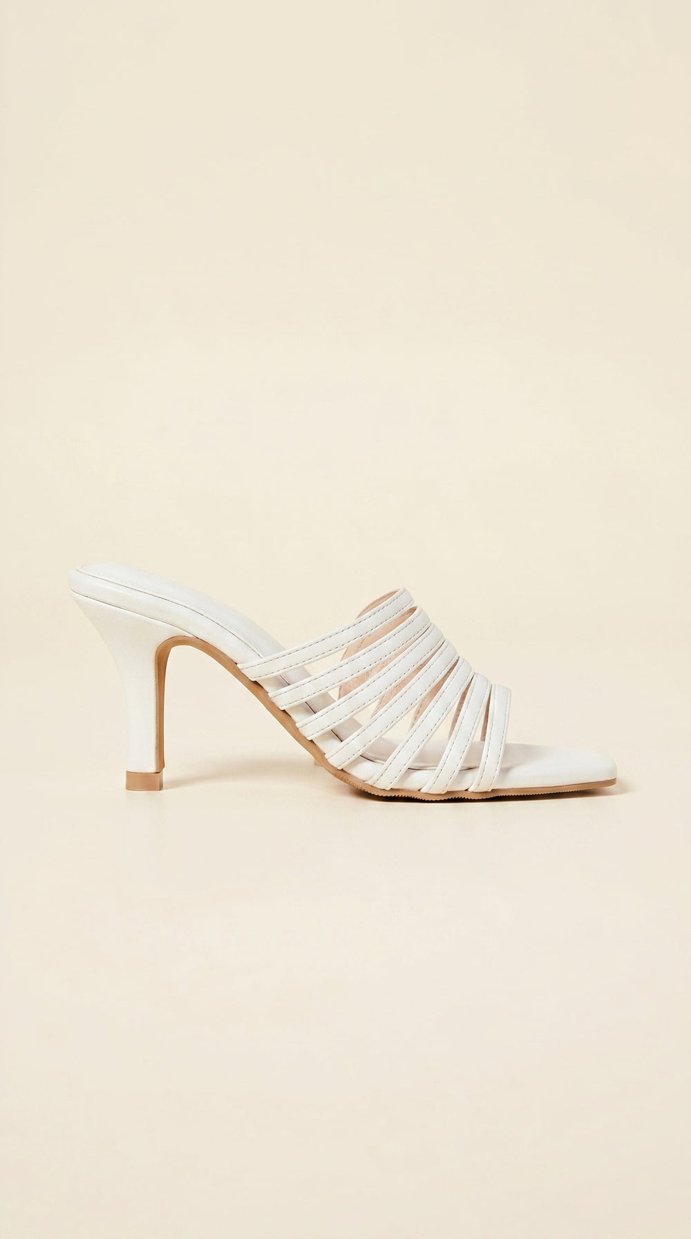 White strappy high-heeled shoe on a beige background