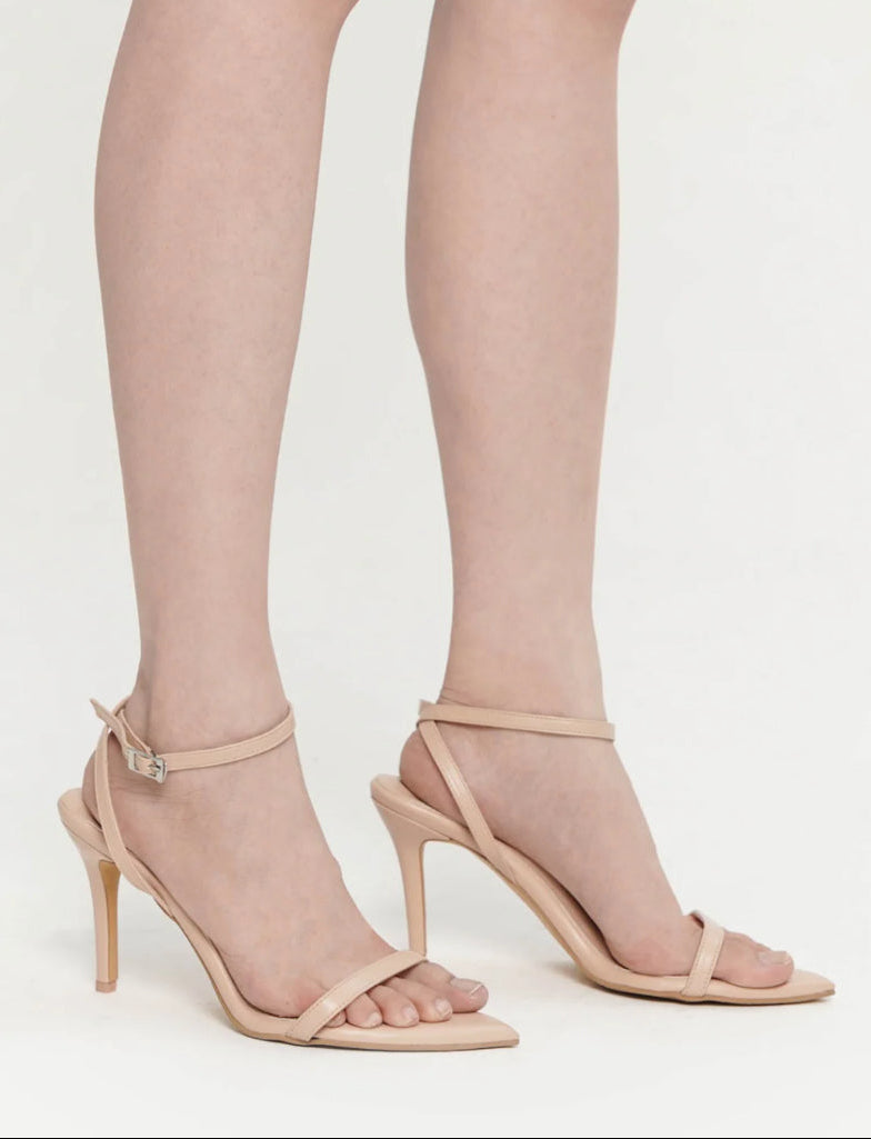 cream nude high-heeled sandals worn with sheer stockings on a light gray background
