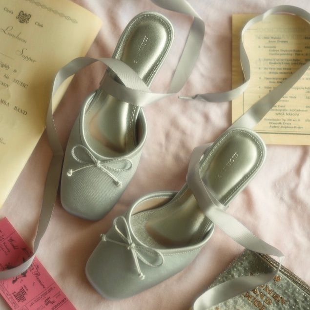 ash blue shoes with ribbons on a pink surface with printed text.