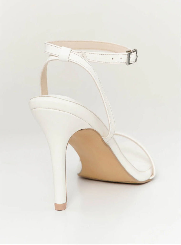 White high-heeled sandal on a light gray background