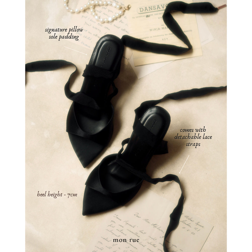 Black pointed-toe shoes with lace straps on a textured surface with text overlay.
