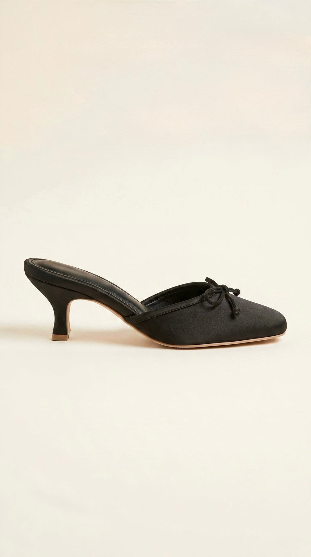 Black mule shoe on a light beige background
