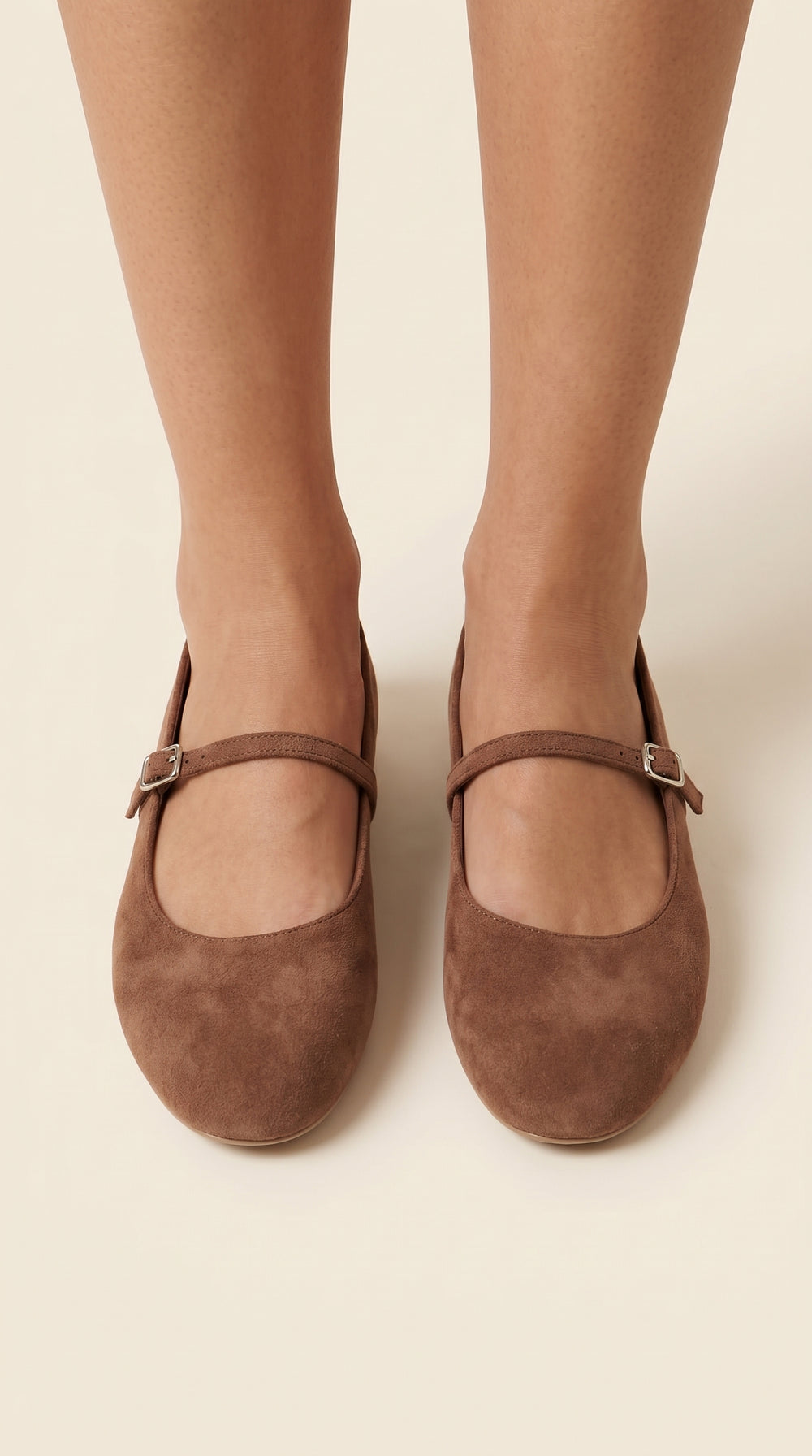 Brown suede shoes worn with beige tights on a plain background