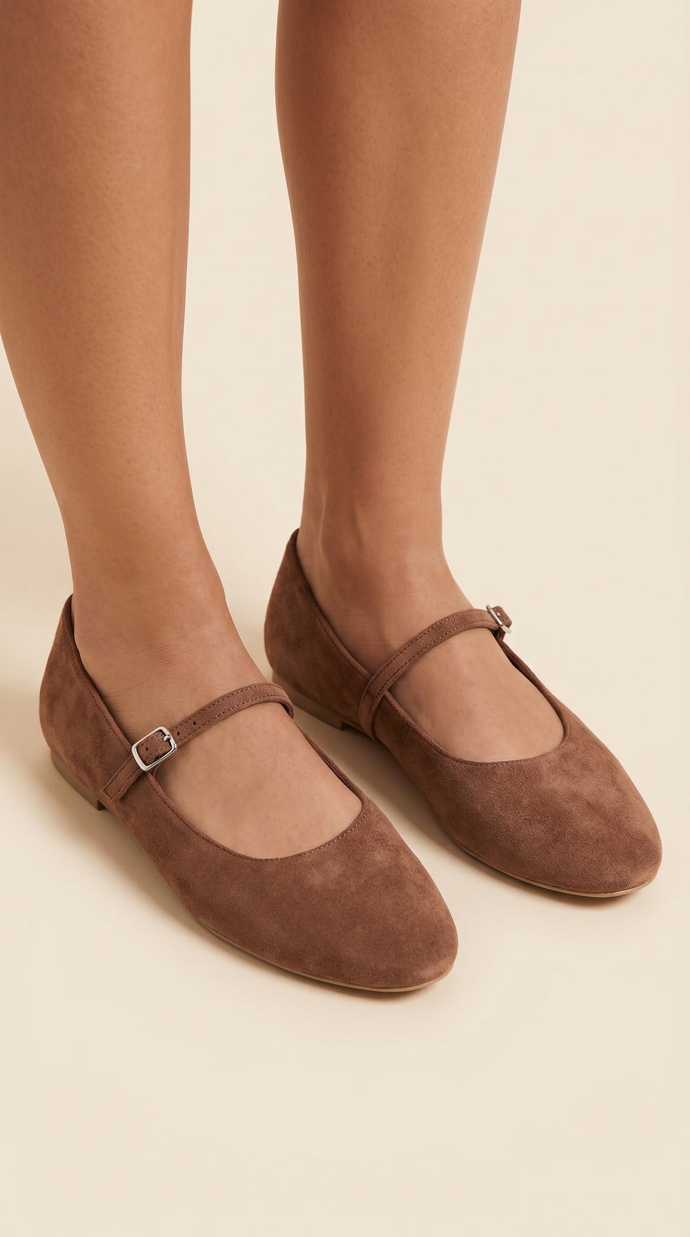Brown suede shoes with a strap on a beige background