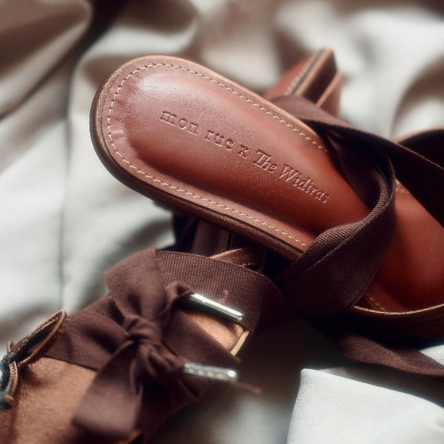 Brown sandal with visible brand name on a soft fabric background