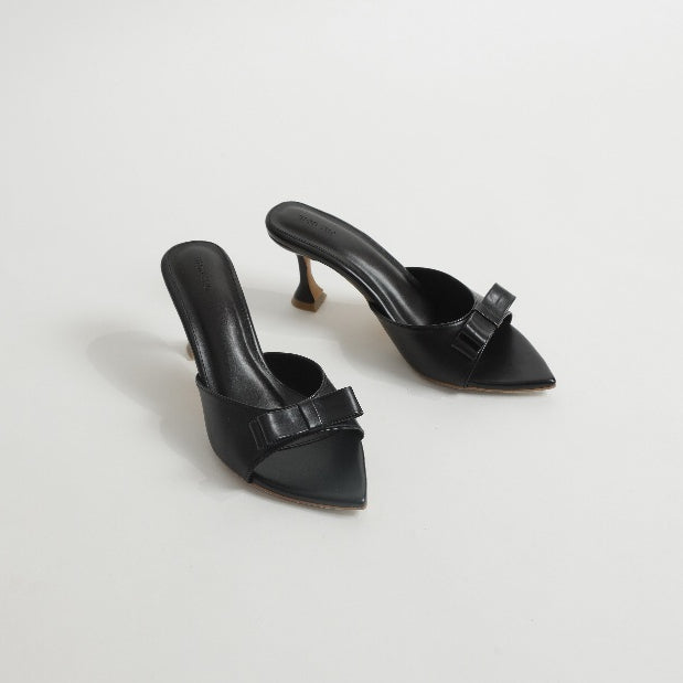 Pair of black high-heeled shoes with bow details on a light gray background