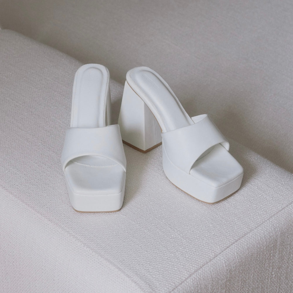 White high-heeled shoes on a textured surface