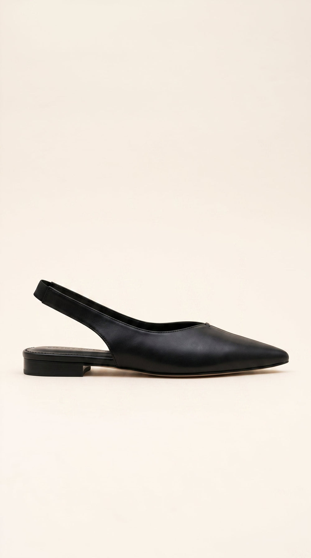 Black leather slingback flat shoe on a beige background