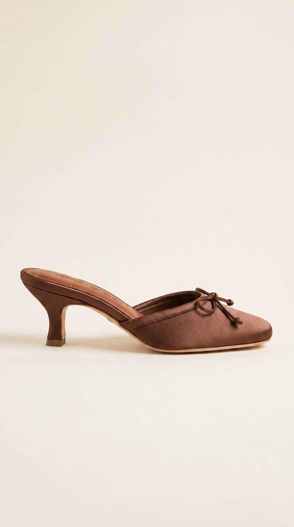 Brown shoe with a bow on a beige background