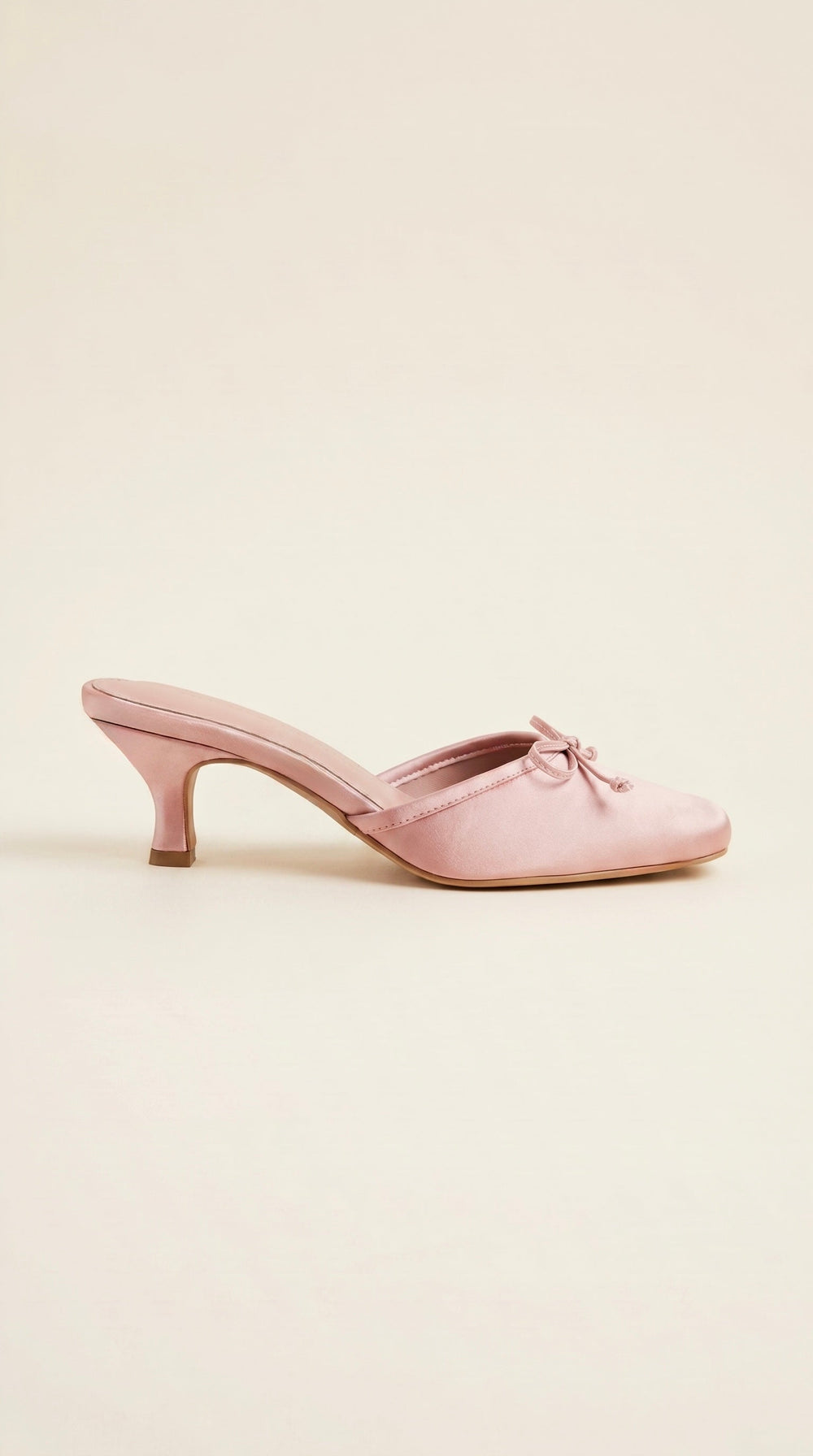 Pink shoe with a bow on a light beige background
