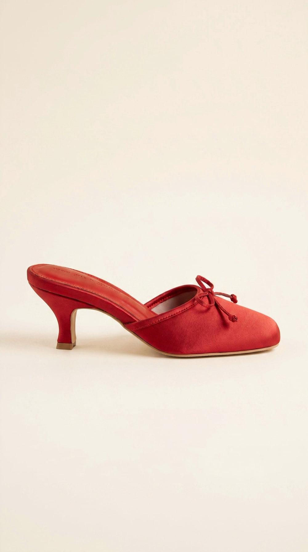 Red shoe with a bow on a beige background